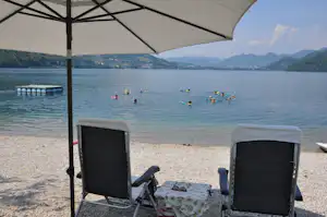 Camping Fleiola - Liegestühle und Sonnenschirme am Strand am Caldonazzo See