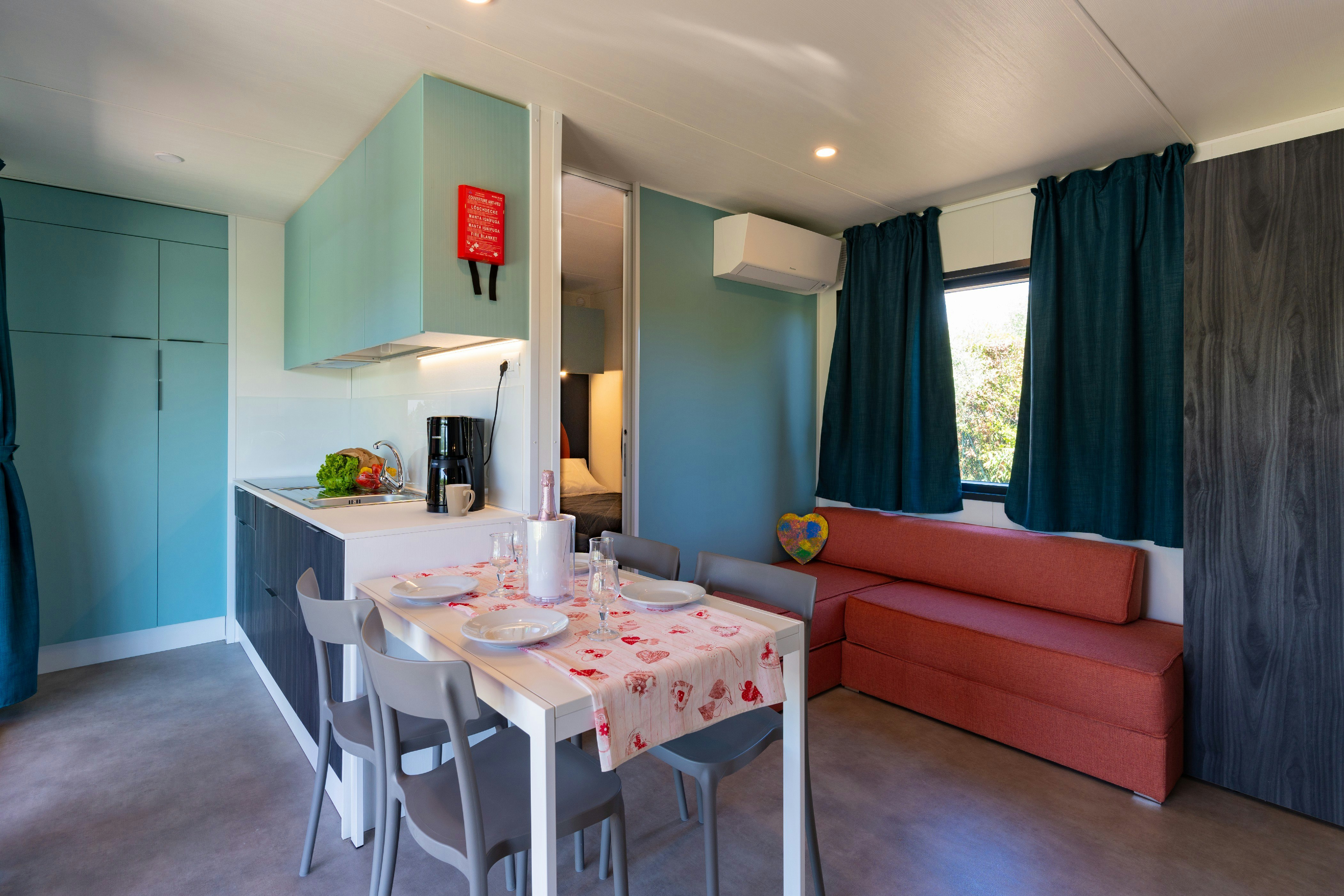 Fornella Camping & Wellness Family Resort  Camping Fornella - Innenansicht eines Mobilheims mit Küche und Esstisch