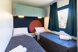 Fornella Camping & Wellness Family Resort Camping Fornella - Schlafzimmer mit zwei Einzelbetten in einem Mobilheim