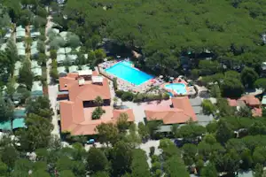 Luftaufnahme einer Campinganlage mit mehreren Schwimmbecken, umgeben von Bäumen und mehrstöckigen Gebäuden mit Terrassen.