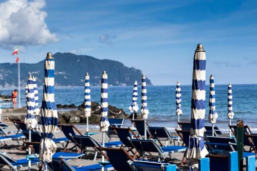 Camping-Liegeplätze mit blauen Sonnenschirmen am Meer, im Hintergrund Berge und Küste.