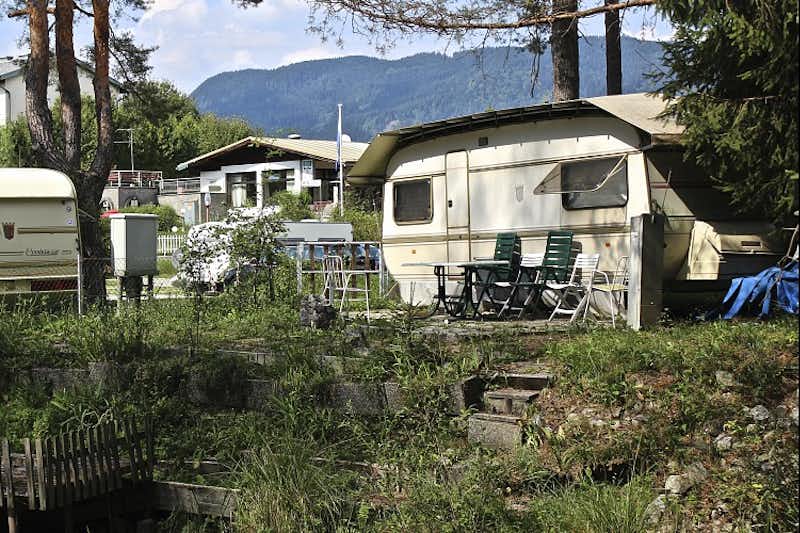 Camping Gerli - Wohnwagen auf einem Stellplatz im Grünen mit Gebäude des Campingplatzes im Hintergrund
