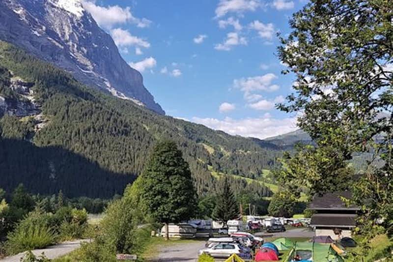 Camping Gletscherdorf  -  Wohnwagen- und Zeltstellplatz zwischen Bäumen mit Blick auf die Berge