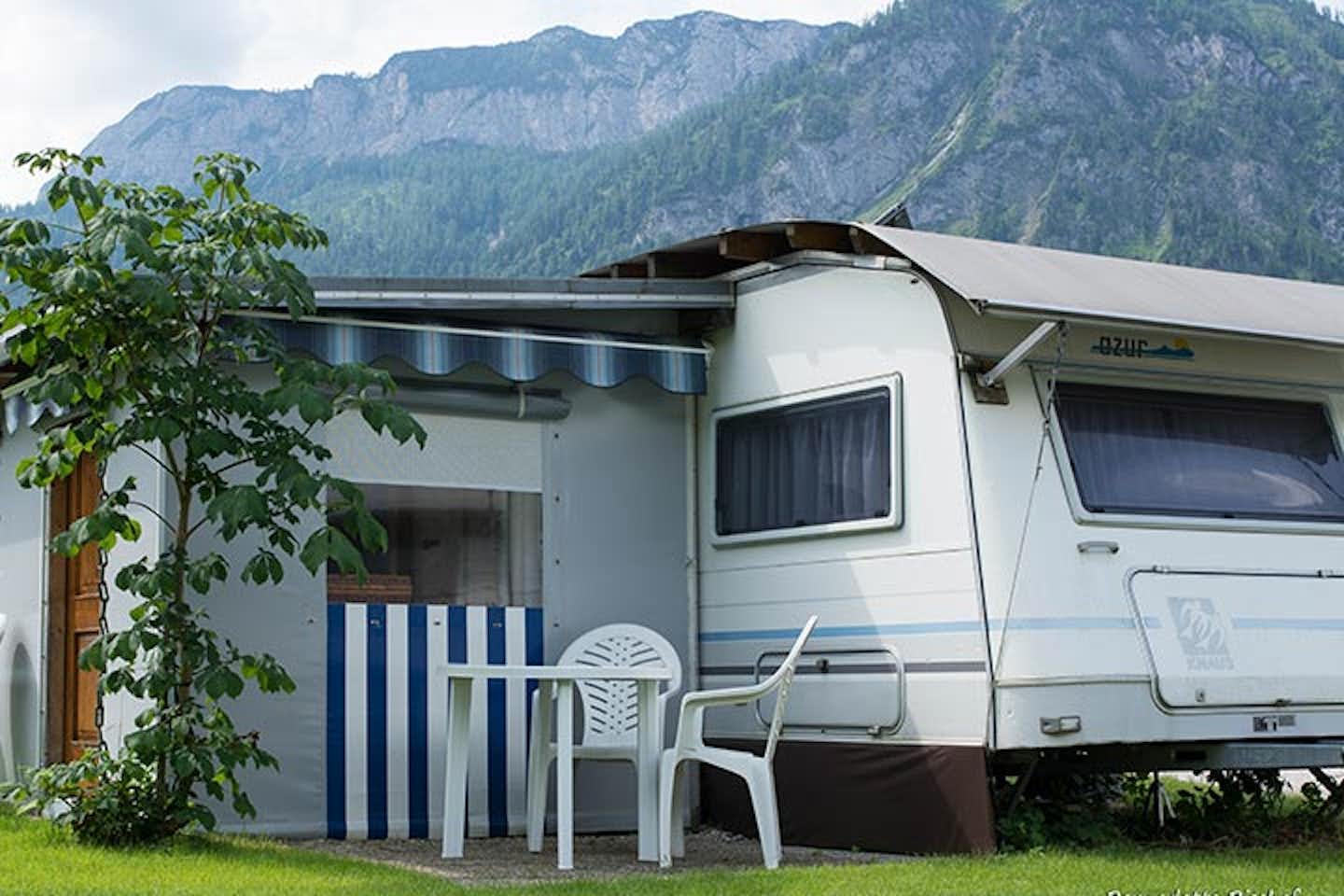 Camping Gößl - Wohnwagen mit Vorzelt mit den Bäumen im Hintergrund