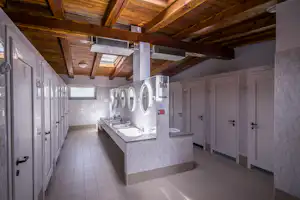 Camping Gran Bosco - Innenraum des Sanitärgebäudes mit Toilettenkabinen und Waschbecken
