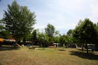Camping Green - Spielplatz auf dem Campingplatz zwischen Bäumen mit Stellplätzen im Hintergrund