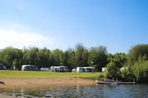 Camping Halen - Blick auf die Stellplätze am See mit Liegewiese und Bootsanlegestelle