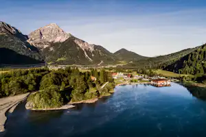 Camping Heiterwanger See - Blick auf den Campingplatz am See mit Berglandschaft im Hintergrund