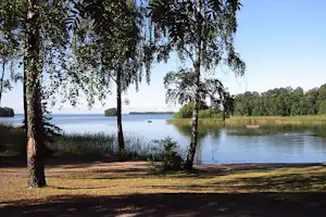 Badestrand mit Schatten spendenden Bäumen des Campingplatzes Herrfallet