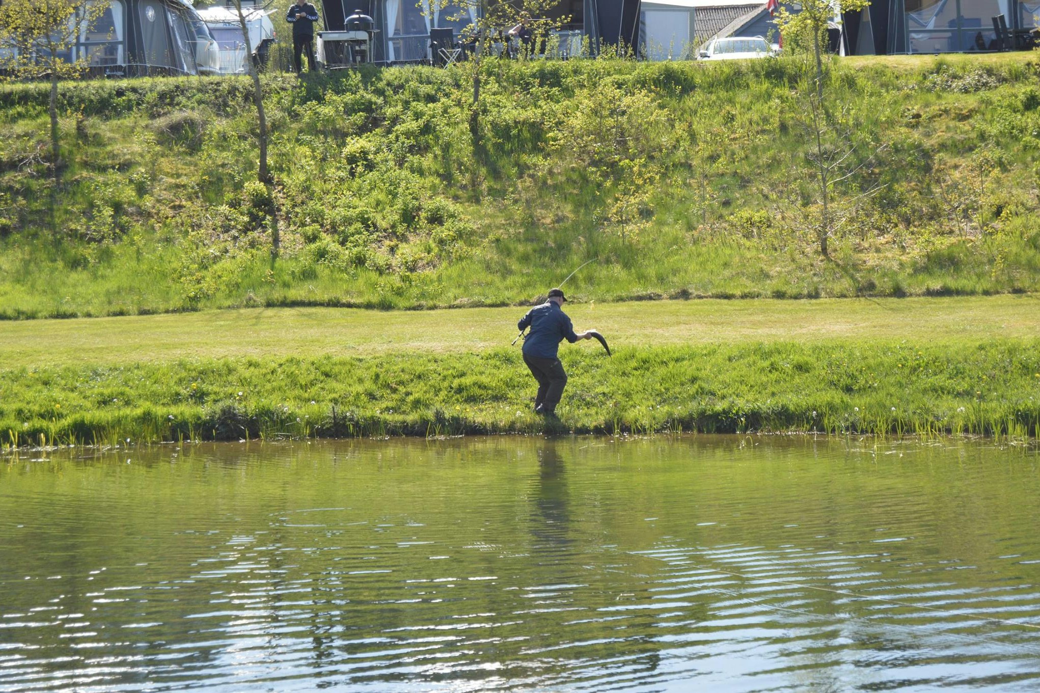 Camping Hessellund Sø - Angler am See, der einen Fisch in der Hand hält