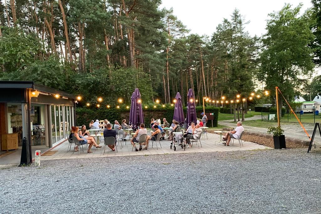 Camping Het Swinnenbos - Geselliger Abend auf der beleuchteten Terrasse umringt von Bäumen