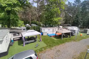 Camping Het Swinnenbos - Luftansicht einiger großer Standplätze mit Mobilheimen und Pavillons umringt von Laubbäumen und Nadelbäumen