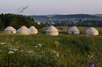 Camping Hofgut Hopfenburg  - Jurten vom Campingplatz auf grüner Wiese mit Blick auf Münsing