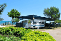 Camping Holiday Village - Wohnwagen unter Sonnenschutz auf einem Stellplatz