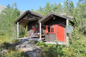 Camping Hov Hyttegrend - Holzhütte mit Terrasse und Sofa zwischen den Bäumen auf dem Campingplatz