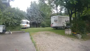 Wohnmobil auf einem Stellplatz im Grünen, mit Kiesweg, Rasenfläche und Bäumen im Hintergrund.