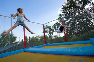 Camping i Pini- Kinder spielen auf einer Sprungmatte auf dem Campingplatz