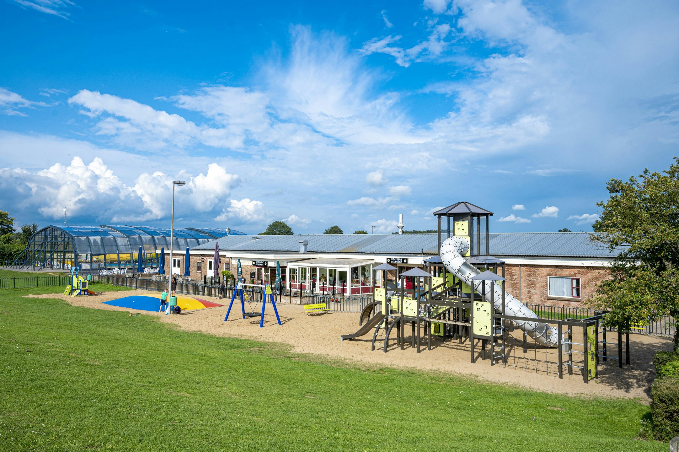 Camping IJsselstrand - Blick auf den Spielplatz mit Klettergerüst, Schaukeln und Hüpfburg