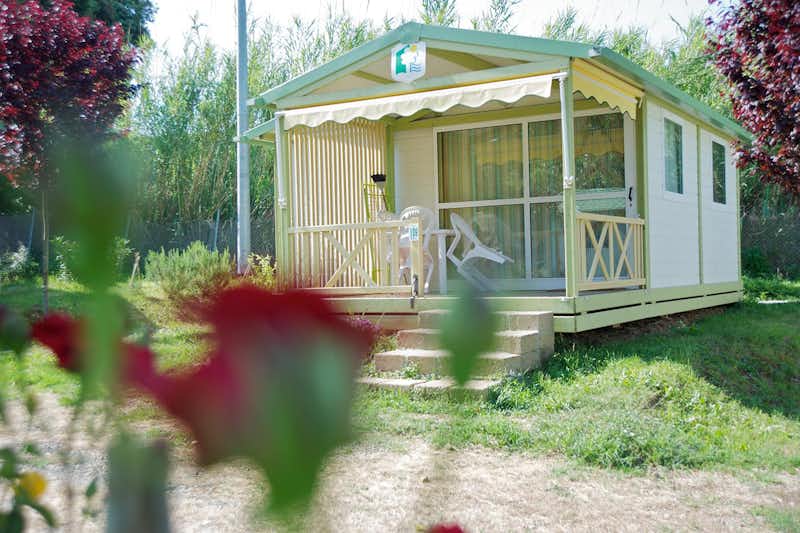 Camping Il Fontino - Mobilheim mit überdachter Veranda, auf der Sitzgelegenheiten stehen