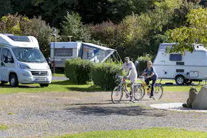 Camping im Thermenland - Radler auf einem Weg des Campingplatzes mit Wohnwagen im Hintergrund