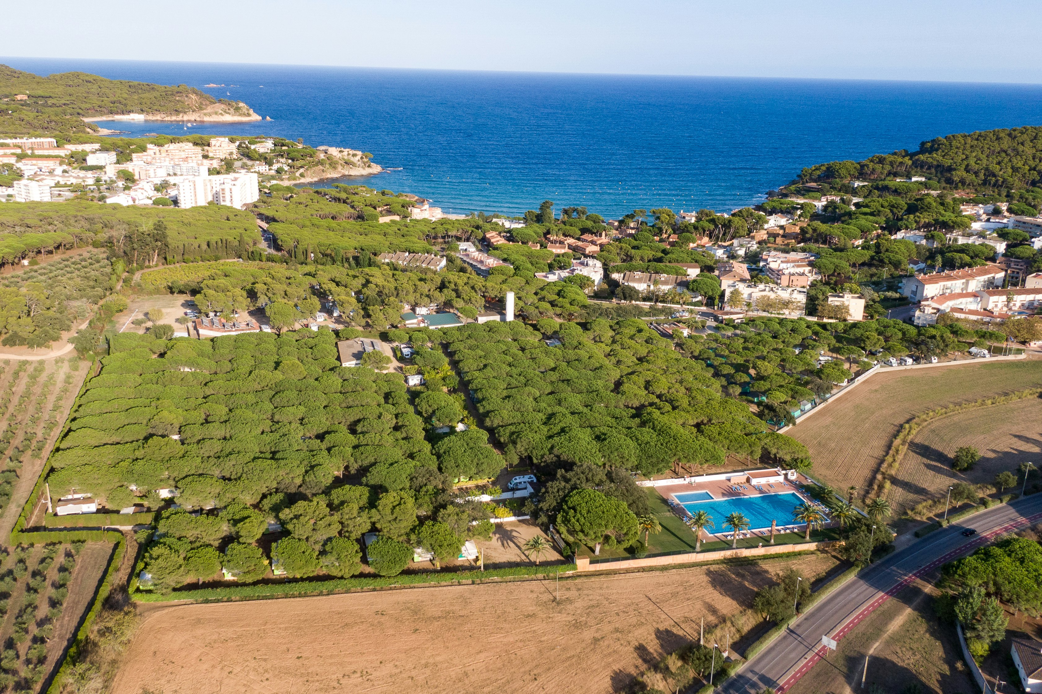 Luftaufnahme einer Küstenanlage mit Wohnhäusern, Feldern, Wegen und einem kleinen Pool nahe dem Meer.