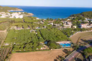 Luftaufnahme einer Küstenanlage mit Wohnhäusern, Feldern, Wegen und einem kleinen Pool nahe dem Meer.