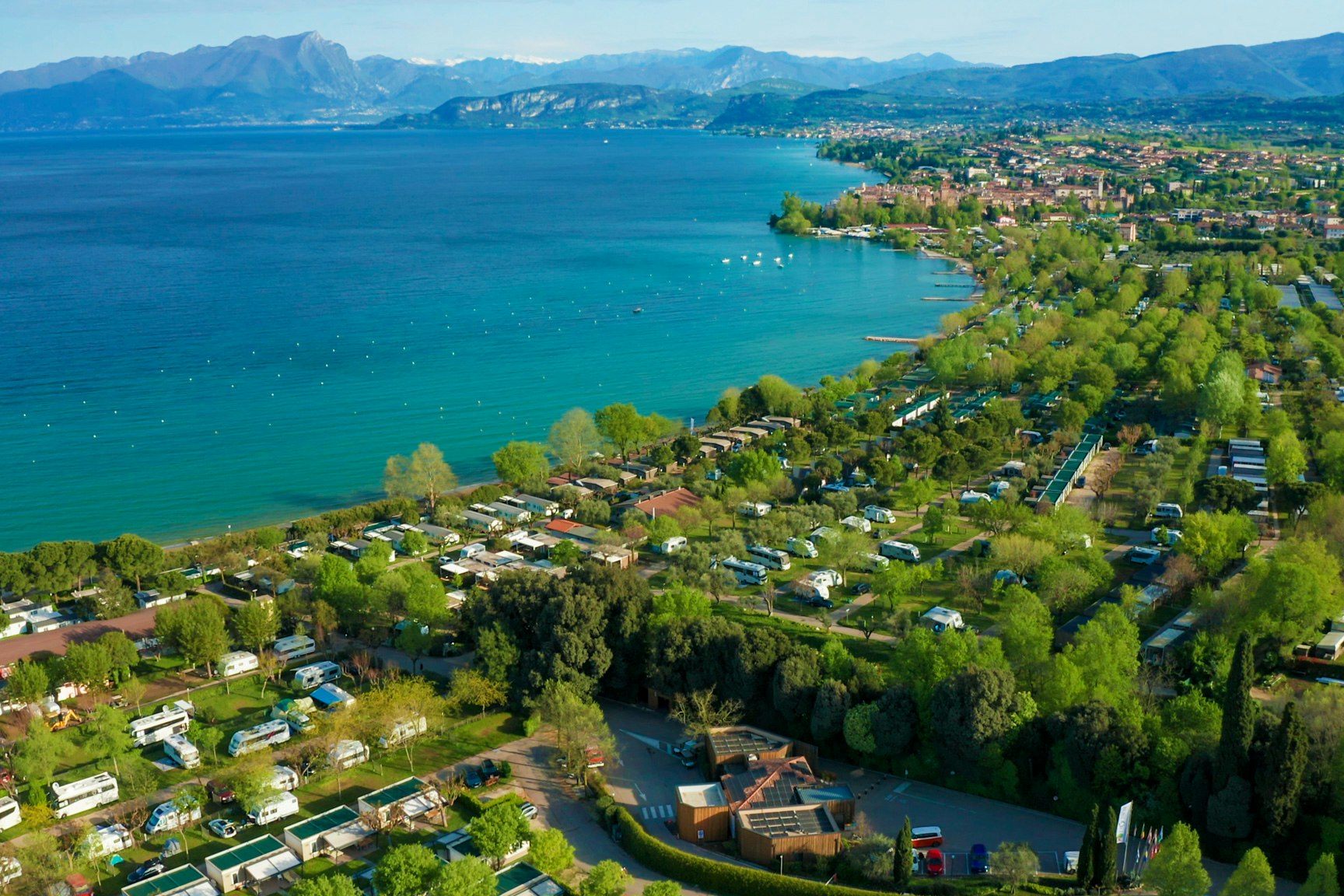 Camping La Quercia  Camping Internazionale La Quercia  - Luftaufnahme des Campingplatzes am Wasser mit Bergen im Hintergrund