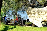 Camping Internazionale Lago di Bracciano - Zeltplatz zwischen den Bäumen auf grünem Rasen mit Blick auf Braccianosee