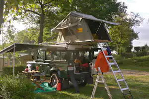 Camping Iserand - Campingjeep mit Zeltkonstruktion auf dem Dach auf einem Stellplatz