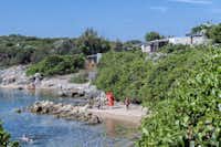 Camping Isola dei Gabbiani - Strand des Mittelmeers mit Ferienhäusern im Grünen dahinter