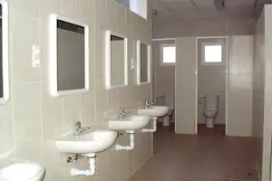 Camping Iznate - Innenbereich des Sanitärgebäudes mit Waschbecken und Blick auf die Toilettenkabinen