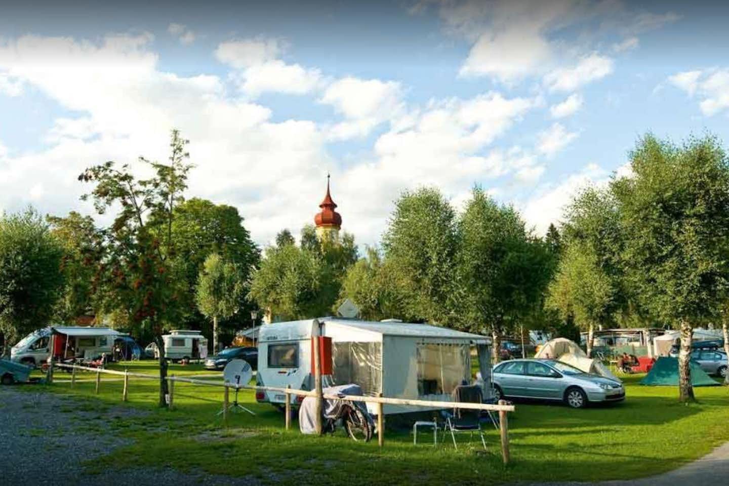 Camping Judenstein  -  Wohnwagen- und Zeltstellplatz vom Campingplatz auf grüner Wiese, Kirche im Hintergrund