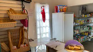 Küchenzeile im Campingbereich mit Holzregalen, Brotkorb, Kühlschrank und Vorratsregal mit Lebensmitteln.