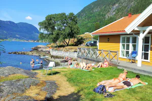 Camping Kjørnes - Gäste liegen in der Sonne am Badestrand vor dem Campingplatz