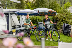 Camping Knaller - Camper mit Fahrrädern vor ihrem Wohnwagenstandplatz
