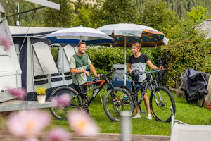 Camping Knaller - Camper mit Fahrrädern vor ihrem Wohnwagenstandplatz