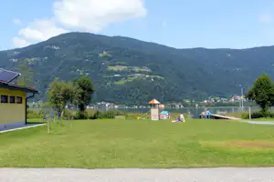 Camping Kölbl - Wiese auf dem Campinggelände mit Kinderspielplatz im Hintergrund am Ossiacher See