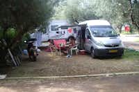 Camping Koróni - Wohnmobil auf einem Stellplatz mit essenden Campern, die davor sitzen
