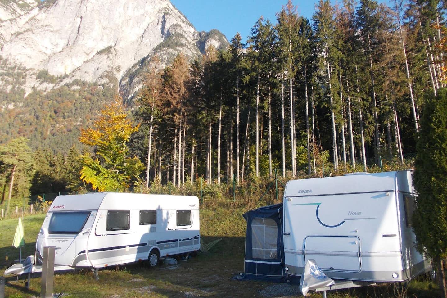Camping Kranebitterhof - Wohnwagen auf Stellplätzen vor einem Waldstück mit Berg im Hintergrund