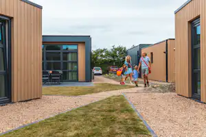 Camping Kreekebos - Familie läuft zwischen den Mobilheimen des Campingplatzes
