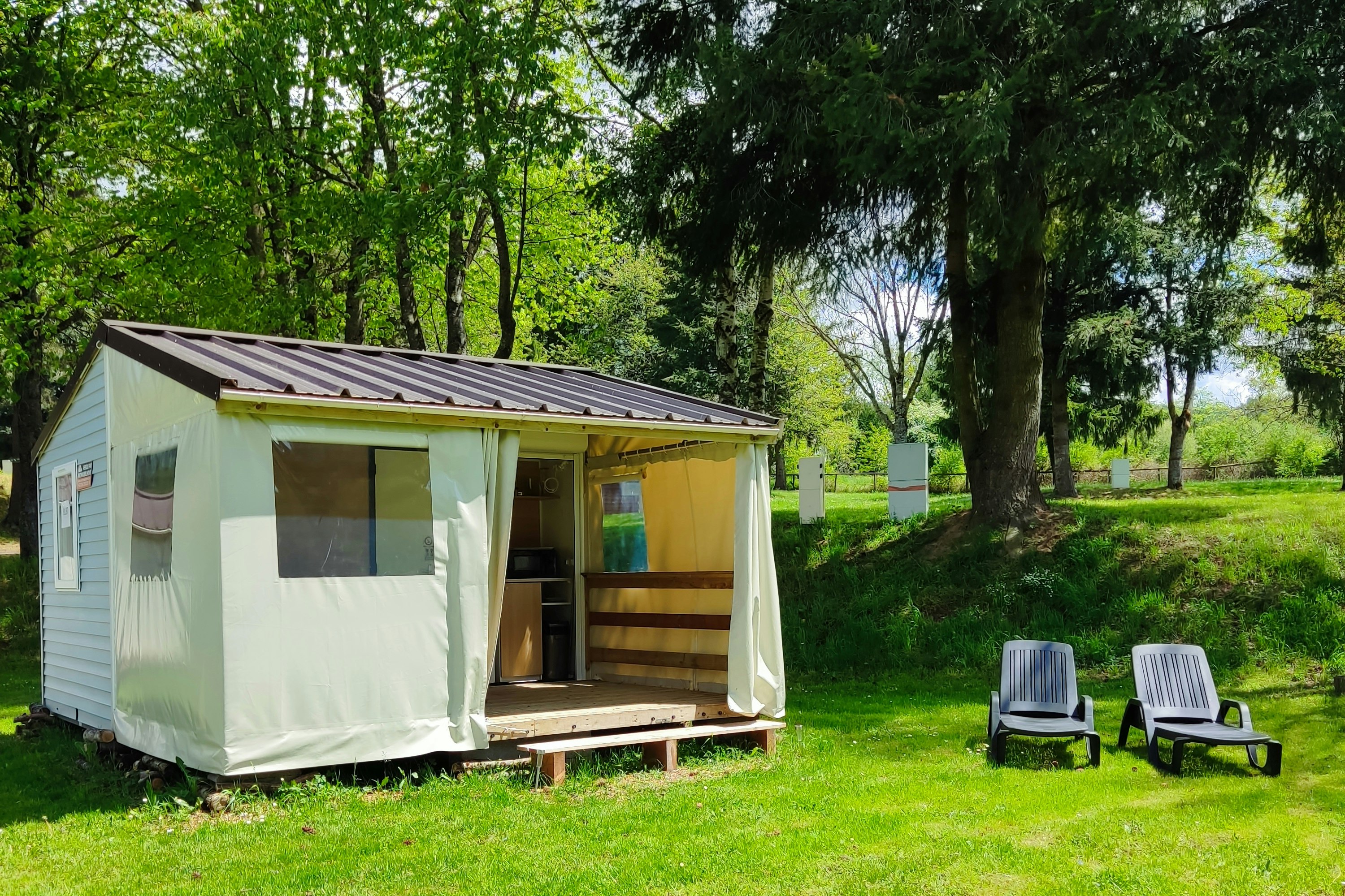 Camping l'Émeraude du Lac - Mobilheim auf der Wiese mit zwei Liegestühlen