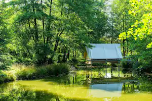 Camping L' Étang de la Fougeraie - Mobilheim vom Campingplatz über dem Wasser zwischen Bäumen