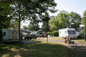 Camping La Belle Étoile - Kinder fahren Kinderauto auf dem grünen Gelände vom Campingplatz