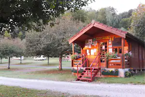 Rezeption in einem Holzgebäude mit Treppe und Veranda, umgeben von Bäumen und einem Kiesweg auf dem Campingplatz.