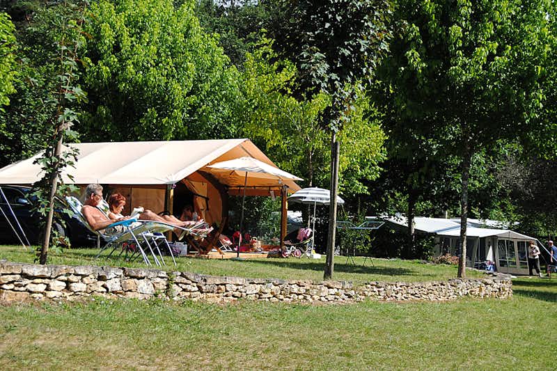Camping La Castillonderie - Glampingzelt auf dem Campingplatz vor dem ein Paar die Sonne genießt