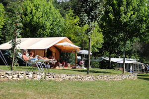 Camping La Castillonderie - Glampingzelt auf dem Campingplatz vor dem ein Paar die Sonne genießt