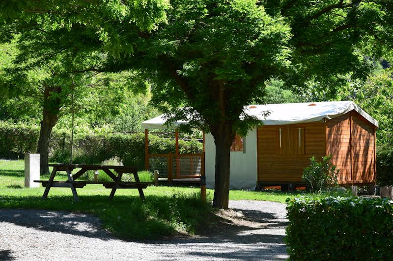 Camping La Charderie - Mobilheim mit überdachter Veranda und Sitzgelegenheiten zwischen Bäumen