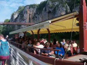 Gelbes Zelt mit Holzgeländer und vielen Gästen auf einer Terrasse, im Hintergrund Felswand und Berglandschaft.