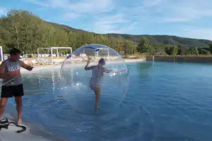 Camping La Célestine - Camperin in einer aufblasbaren Kugel, die auf dem Swimmingpool läuft