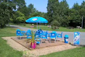 Camping La Fritillaire - eine Terrasse der Snackbar mit Sitzgelegenheiten und Sonnenschirm